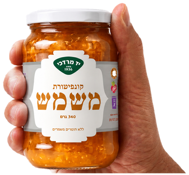 A hand holding the apricot jam jar